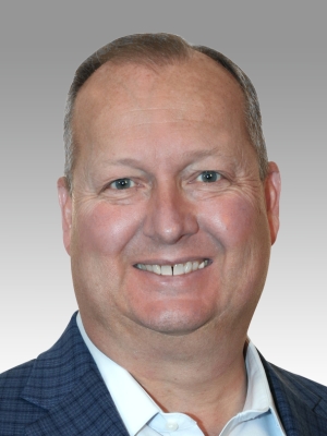 Smiling man in a blue blazer with a light background.